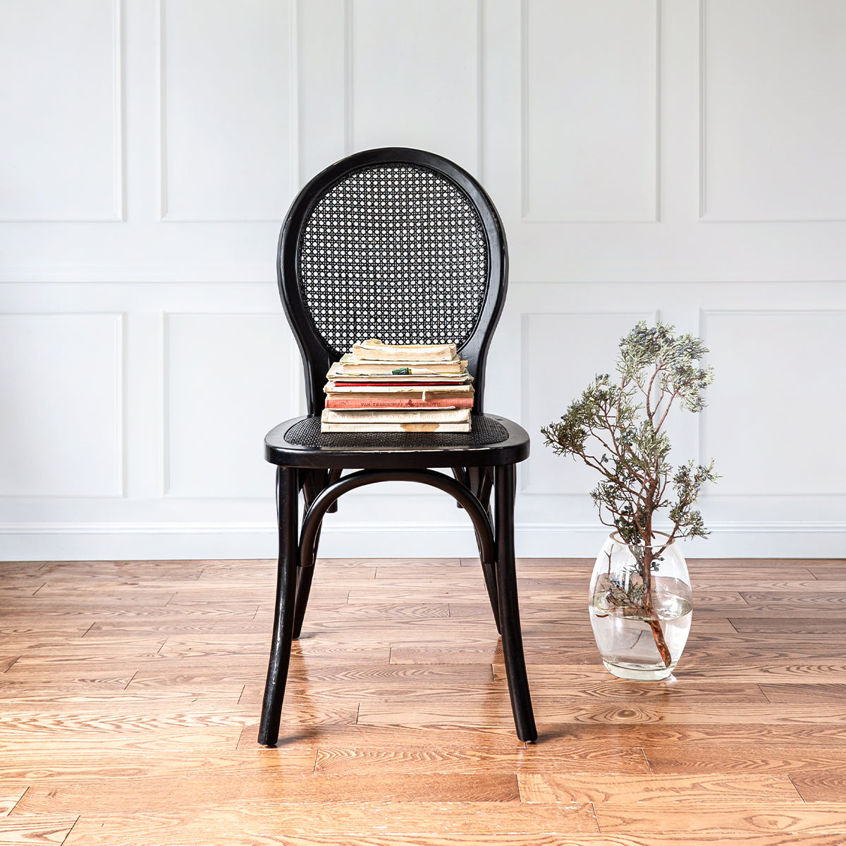 Black painted dining chair with rattan back on wood floors
