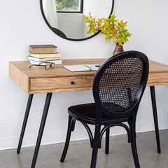 Black painted rattan chair next to a work desk