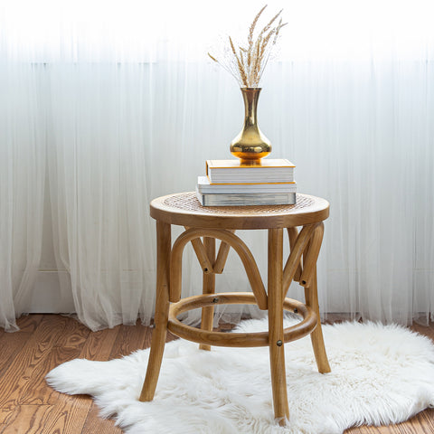 Fleur bohemian stool sitting on a wooden floor with books stacked on top.